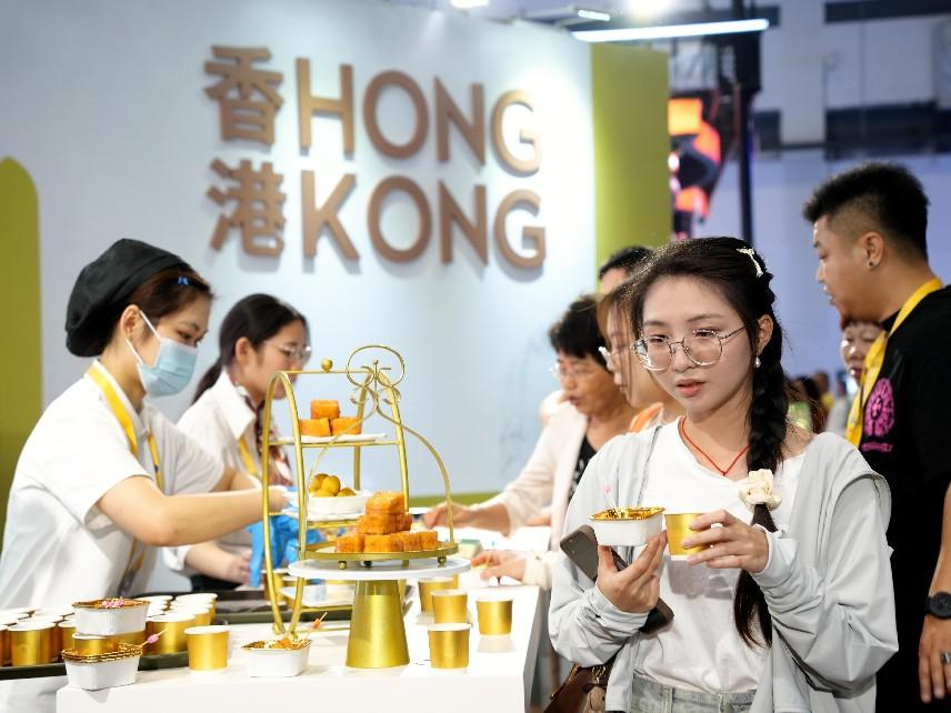 消博会现场，参观者在展台尝试糕点美食。人民网记者 张力洋摄