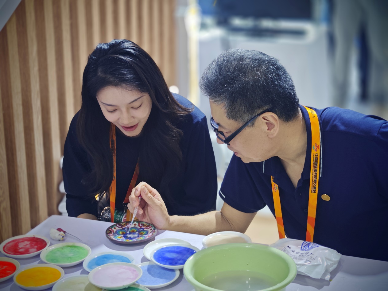 工作人员正在向观众介绍景泰蓝工艺特点。人民网记者 黄盛摄