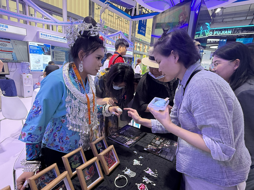 贵州展台工作人员向观众介绍苗绣和银饰等展品。人民网记者 杜燕飞摄