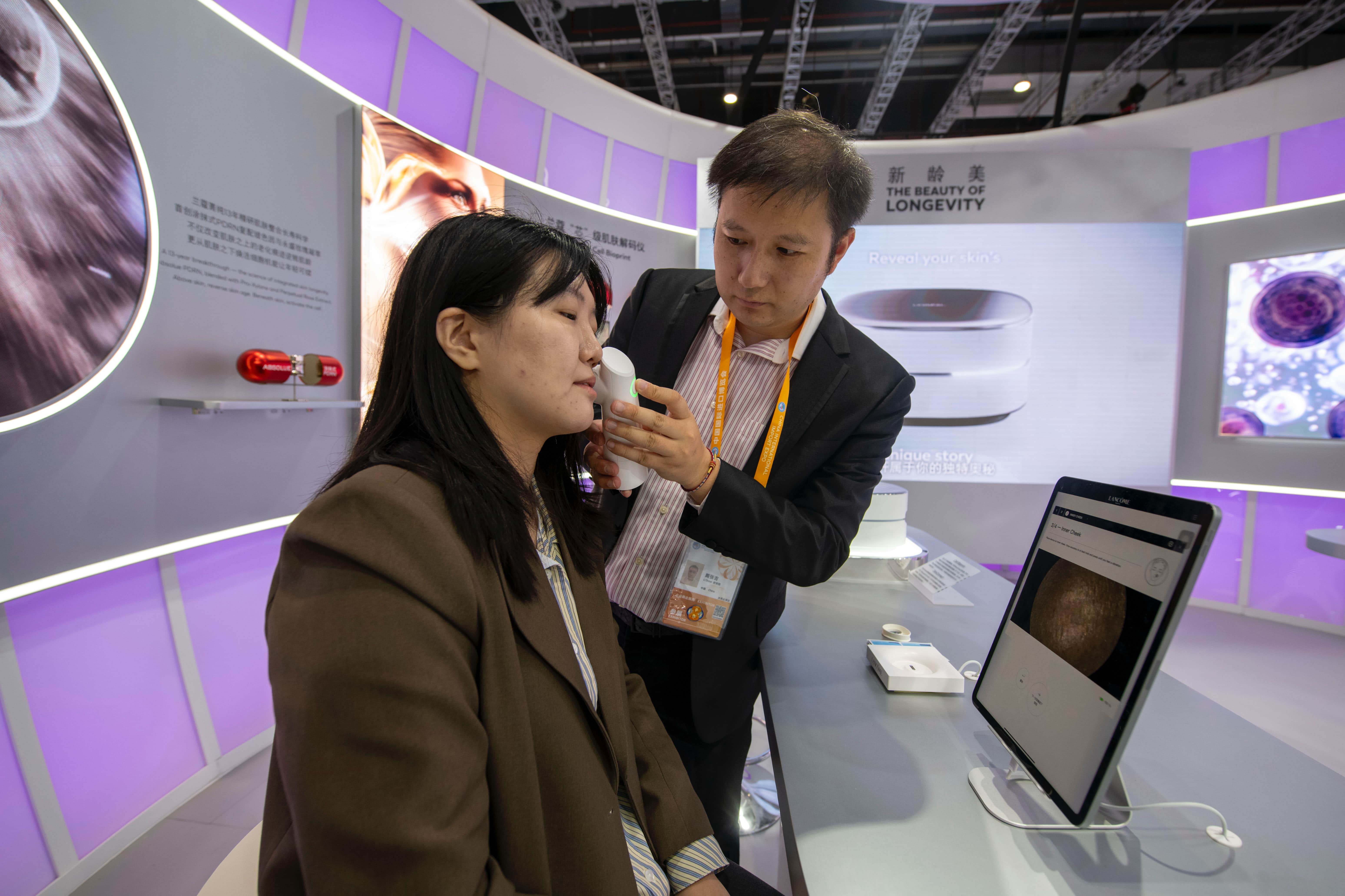 在第八届进博会消费品展区的欧莱雅展台，参观者正在体验中国首秀产品SkinConnect微镜，对脸部皮肤进行全面检测。人民网记者 翁奇羽摄