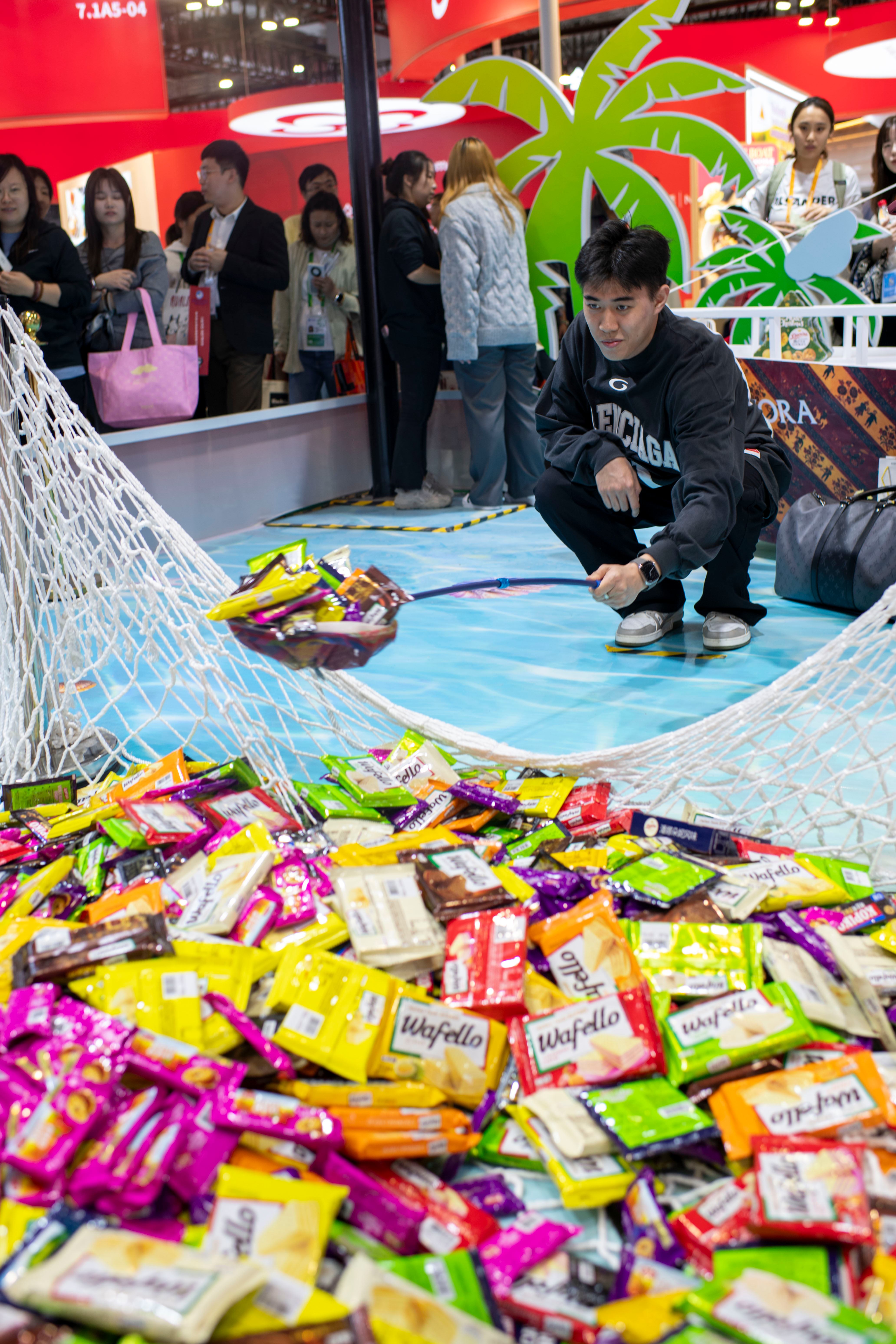 11月7日，在第八届进博会农食产品展区的罗玛展台，参观者通过游戏赢取零食。人民网记者 翁奇羽摄