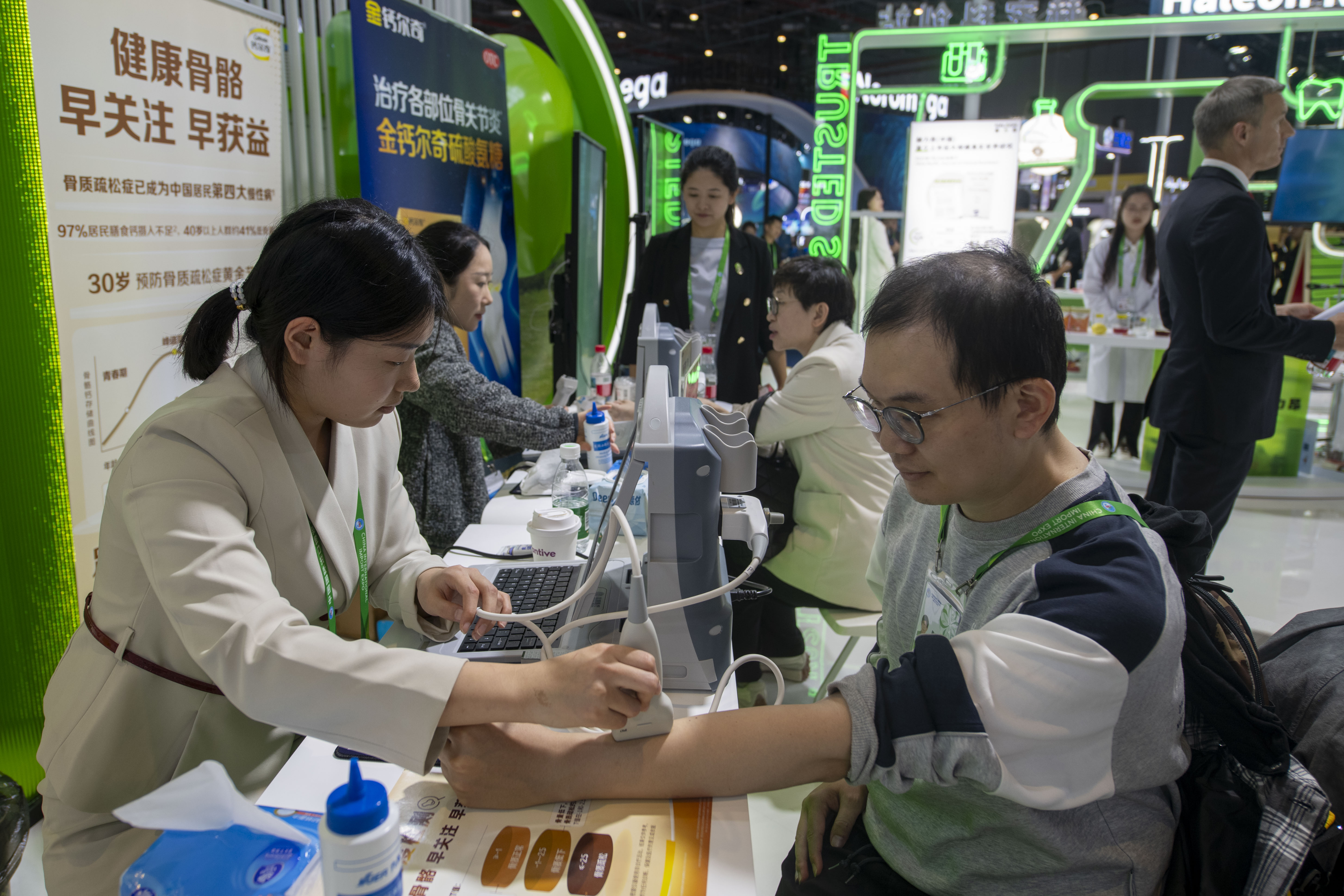 在第八届进博会医疗器械及医药保健展区的赫力昂展台，参观者正在检测骨密度。人民网记者 翁奇羽摄