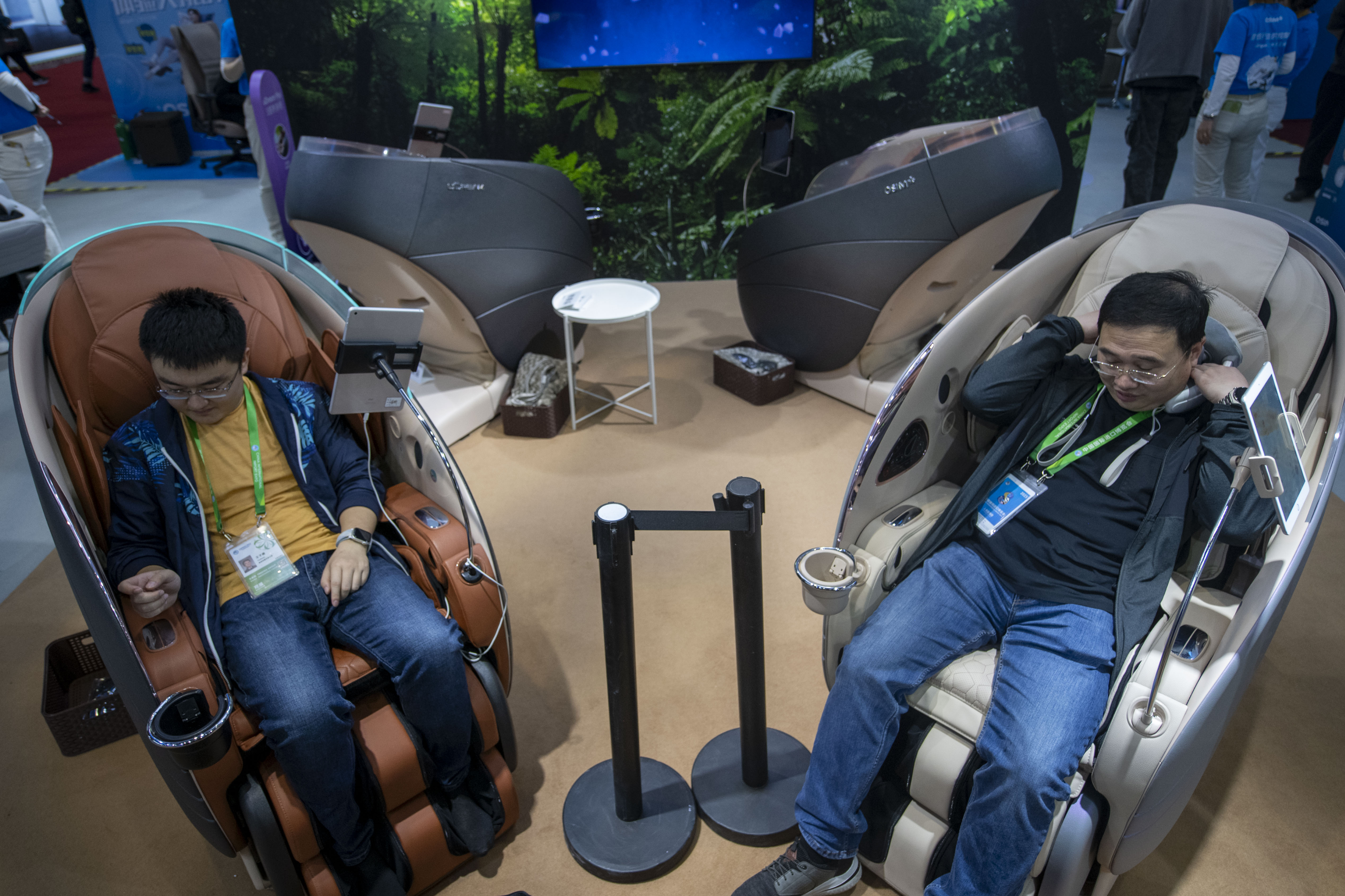 在第八届进博会消费品展区的傲胜展台，参观者体验新款按摩椅。人民网记者 翁奇羽摄