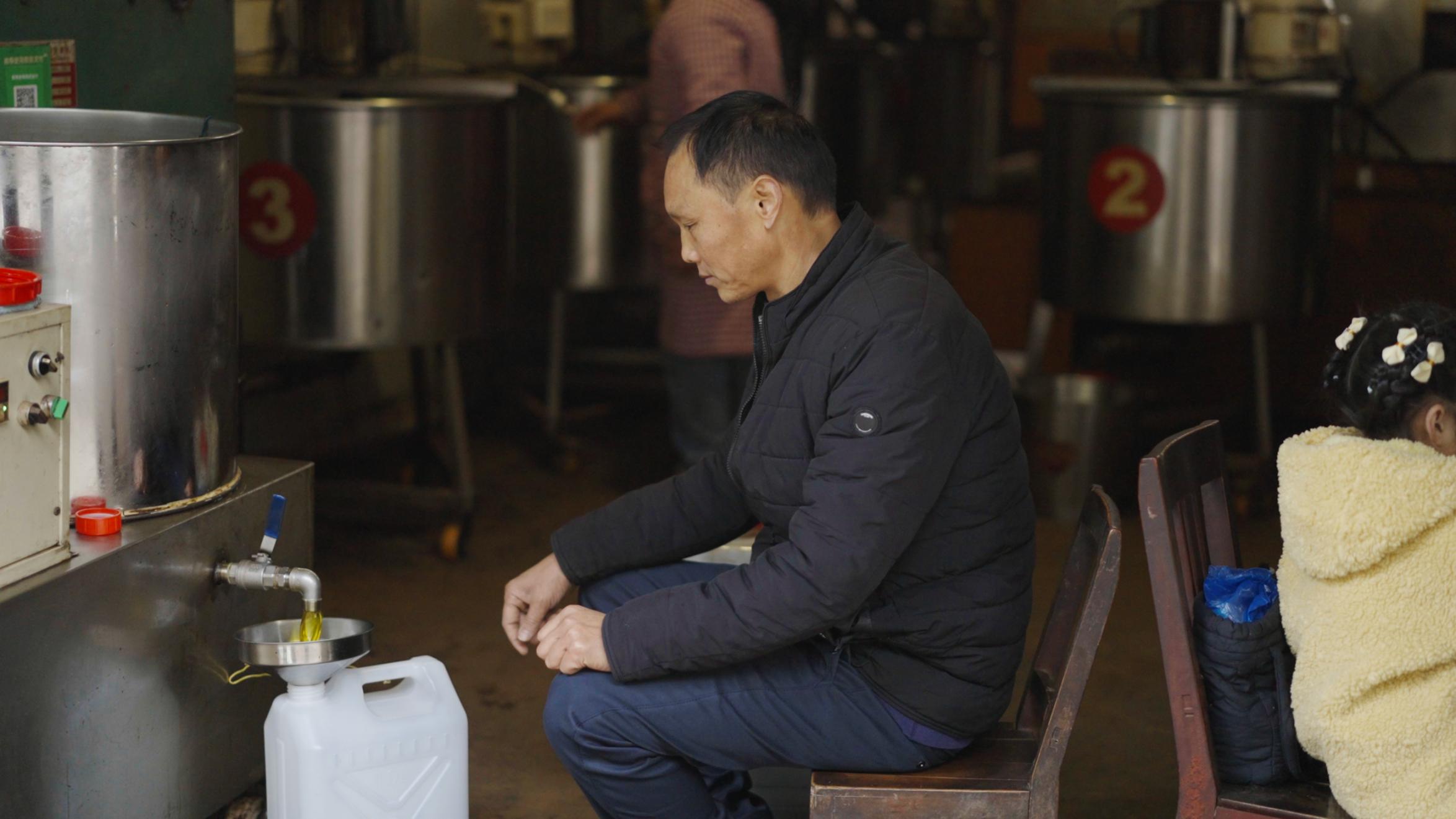 当地居民在油坊灌装新榨菜籽油。人民网记者 王天乐摄