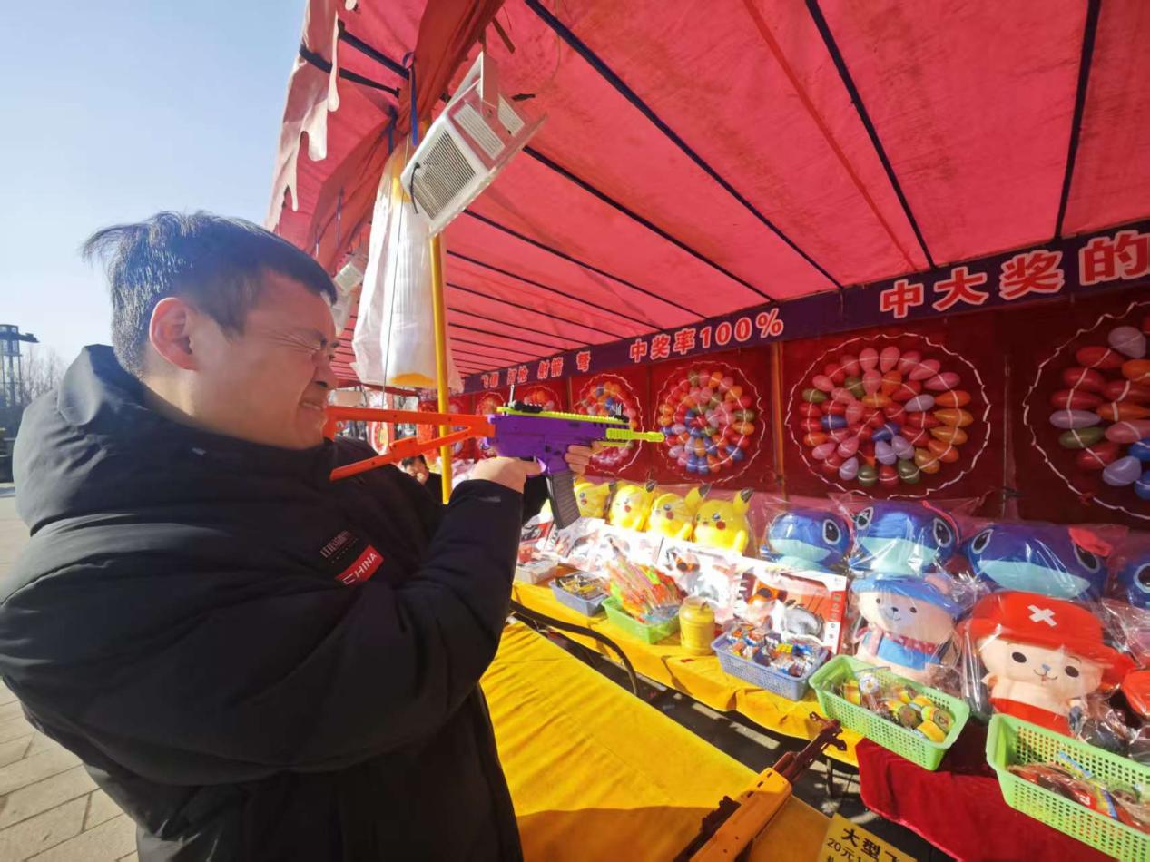 小镇的游戏摊位前，顾客在进行射击游戏。人民网记者 王天乐摄