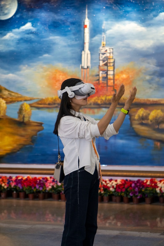 5月22日,酒泉卫星发射中心,在科普活动现场,一位女士正通过VR眼镜,感受星辰大海。人民网记者 翁奇羽摄