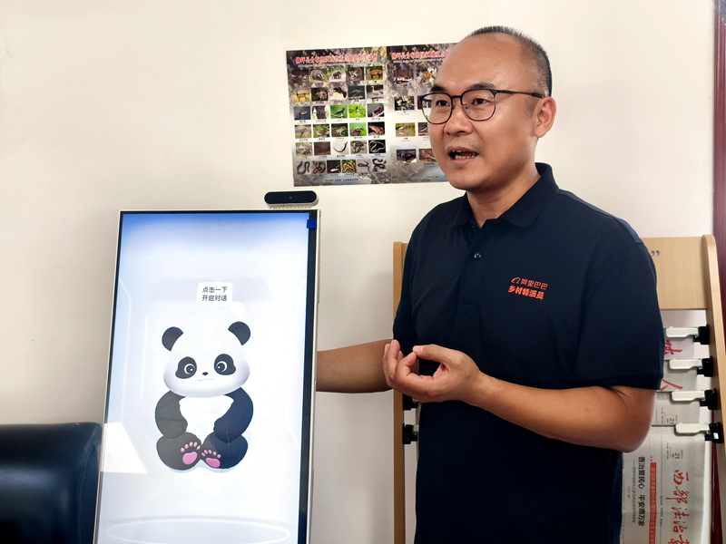 在西岔河镇银厂沟村，已在佛坪扎根五年的阿里巴巴乡村振兴特派员高泉向调研团队介绍AI一体机。人民网记者 孙博洋摄