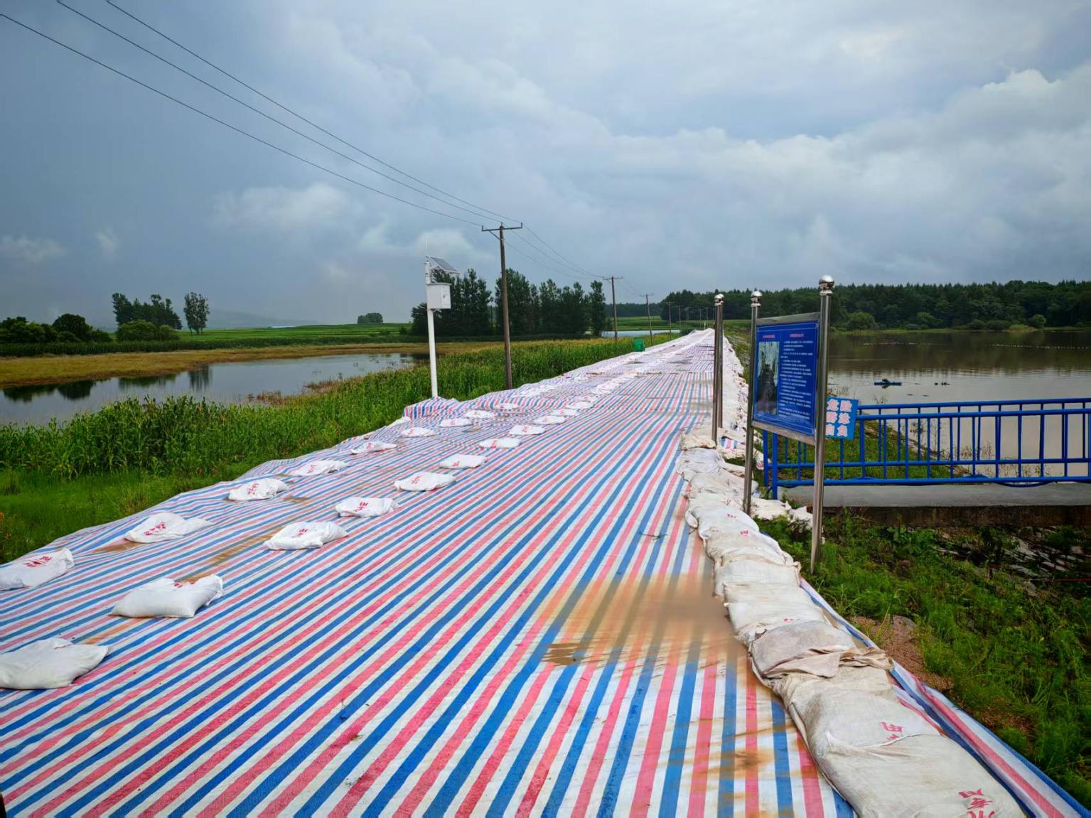 雨后的新发水库坝坡铺满防护彩条布。受访者供图