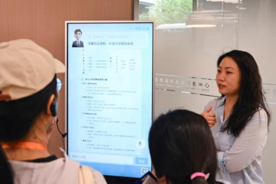 2025年9月10日，上海虹桥海外发展服务中心的工作人员(右)在展示出海服务AI工具。新华社记者 陈浩明 摄